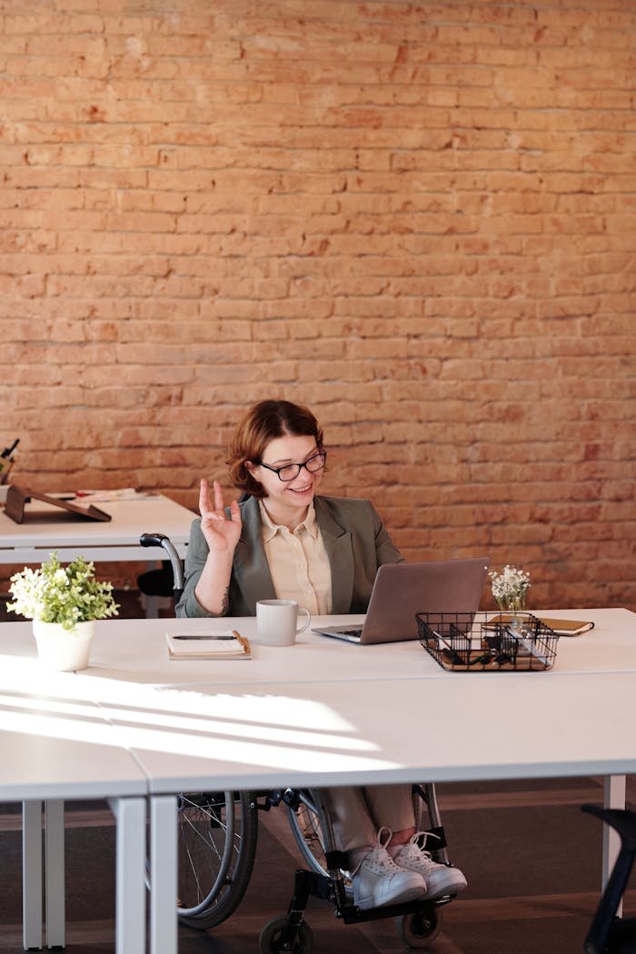 Sobre Nosotros A cheerful businesswoman in a wheelchair working remotely from a modern office setting.